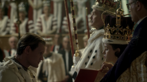 Prince Philip, Duke of Edinburgh kneeling before his wife, the Queen at her coronation in 1953 as portrayed by Claire Foy and Matt Smith in The Crown on Netflix.